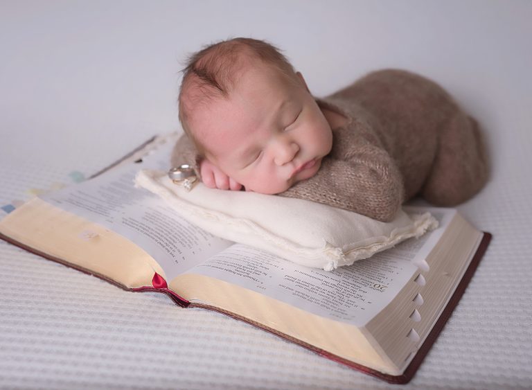 newborn baby with family bible during session